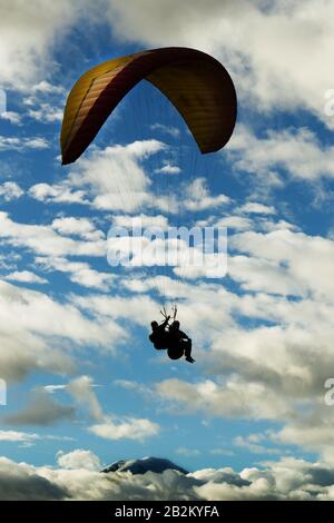 Parapendio in tandem contro il cielo nuvoloso Ande ecuadoriane in background Vulcano Chimborazo Foto Stock