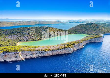 Croazia, isola di Dugi Otok, veduta aerea del lago Salato nel parco naturale Telascica, spettacolari scogliere sul mare Foto Stock