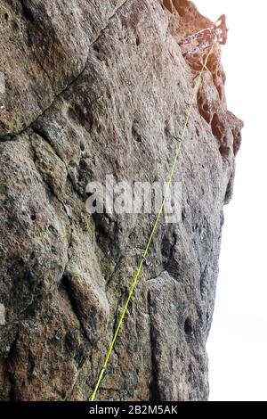 Donna alpinista, giovane alpinista arrampicata un percorso difficile su una roccia. Scalatore sale un muro roccioso. Con fune di sicurezza sulla roccia. Overcomin Foto Stock