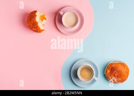 Composizione creativa del mattino da due tazze di ceramica di caffè appena fatto e ciambelle fatte in casa, metà e tutto su un duotone pastello blu rosa Foto Stock