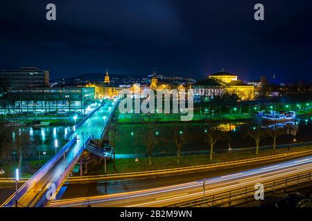 Germania, Bella città saarbruecken in saarland di notte con traffico di guida lungo l'acqua del fiume saar, illuminato in magica atmosfera, vista Foto Stock