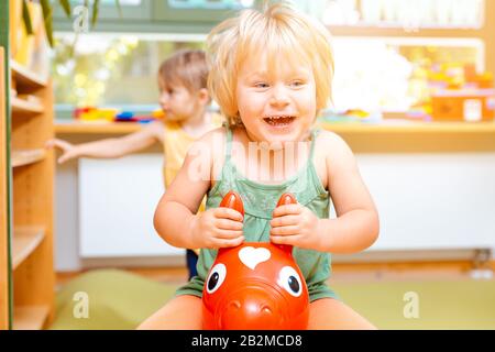 Bambine equitazione nel riprodurre i cavalli in kindergarten Foto Stock