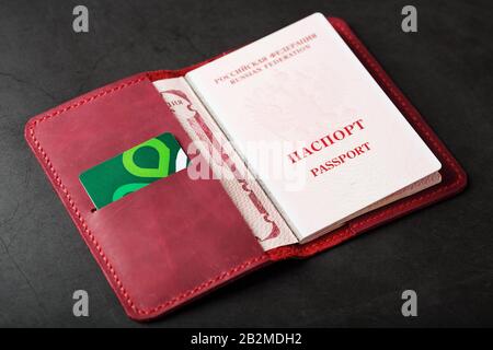 Copertina rossa fatta a mano in vera pelle su sfondo scuro, svelata con un passaporto e una carta elettronica verde. Passaporto di un cittadino Foto Stock