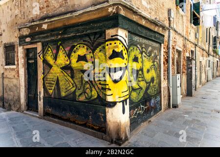 Graffiti gialli su persiane appartenenti ad un negozio a Venezia, Italia Foto Stock