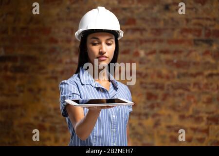 Ingegnere architetto femminile di razza mista che tiene un tablet digitale Foto Stock