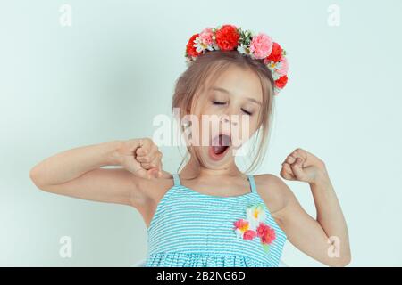 Una giovane donna sorridente in camicia rossa a manica lunga a scacchi stretching. Ritratto di closeup del capretto caucasico con fascia floreale isolata su g bianco Foto Stock