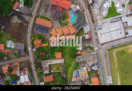 Una fotografia aerea dall'alto cattura un quartiere residenziale e commerciale misto. La scena presenta diversi edifici con caratteristici tetti di tegole arancioni, alcuni disposti in fila con Foto Stock