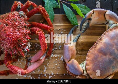 Granchio marrone bollito e granchio ragno nella tavola di legno della cucina, deliziosa preparazione di pesce Foto Stock