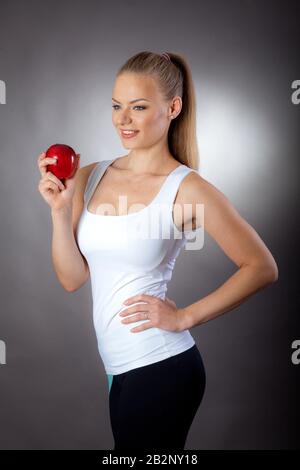 Una donna bella ed elegante mangia un Apple per mantenere una figura sottile Foto Stock