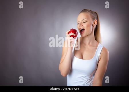 Una donna bella ed elegante mangia un Apple per mantenere una figura sottile Foto Stock