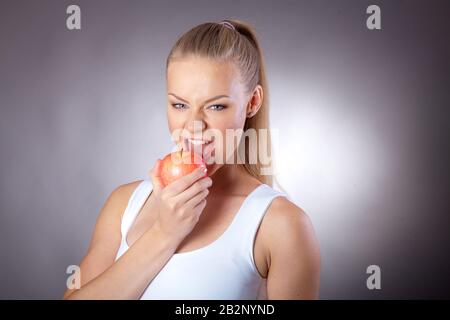 Una donna bella ed elegante mangia un Apple per mantenere una figura sottile Foto Stock