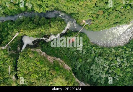 Una fotografia aerea in alto cattura un fiume tortuoso che attraversa una fitta foresta verde. Il fiume presenta numerose cascate e rapide, con acqua bianca in contrasto con il Foto Stock