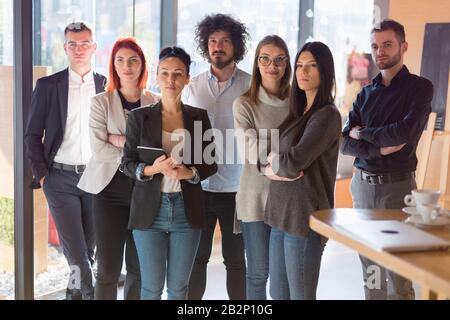 Ritratto di creative di successo team aziendale guardando la fotocamera e sorridente. Attività diverse persone in piedi insieme all'avvio. Foto Stock