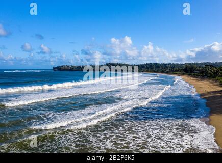 Immagine panoramica aerea all'alba al largo della costa sulla Baia di Hanalei e Princeville dal parco spiaggia di Waioli sull'isola Hawaiiana di Kauai Foto Stock
