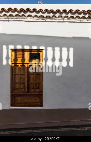 Ombra da una balaustra cade attraverso una finestra di legno con copertura in un astratto dettaglio architettonico, Guia de Isora, Tenerife, Isole Canarie, Spagna Foto Stock