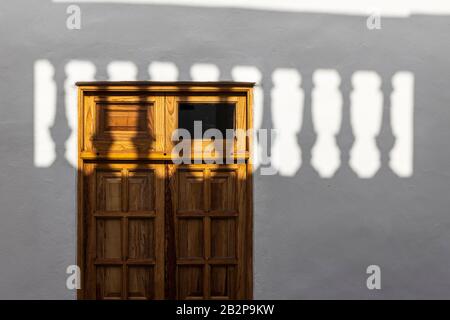 Ombra da una balaustra cade attraverso una finestra di legno con copertura in un astratto dettaglio architettonico, Guia de Isora, Tenerife, Isole Canarie, Spagna Foto Stock