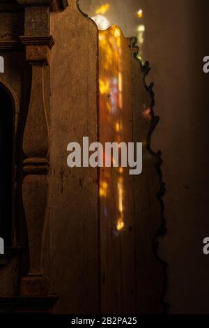Luce solare attraverso una vetrata proietta disegni colorati astratti sul pezzo di un altare di legno in una chiesa, Guia de Isora, Tenerife, Canary i