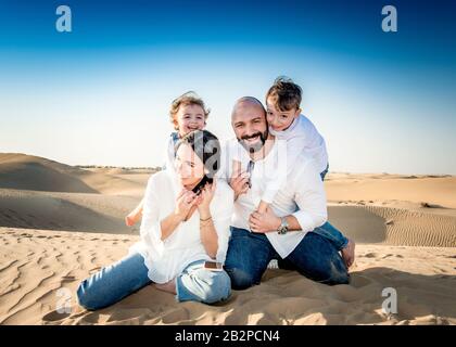 Ritratto di gruppo di famiglia, divertirsi insieme, in un ambiente deserto con dune di sabbia sullo sfondo, Dubai, Foto Stock