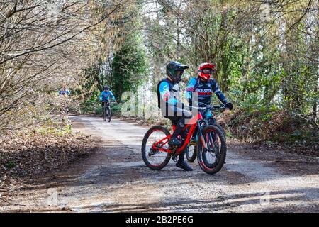 Due ciclisti in primo piano, in piedi sulle loro mountain bike, attendono l'arrivo degli altri atleti del gruppo, prima di iniziare l'allenamento s Foto Stock