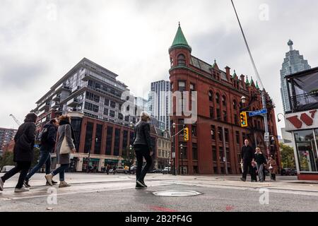 Persone che camminano attraverso la strada di fronte al famoso Gooderham Building / Flatiron Building a Toronto. Foto Stock