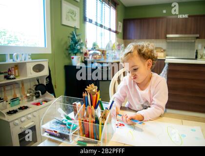 Piccola ragazza a casa che si colorano in su tavolo da cucina. Foto Stock