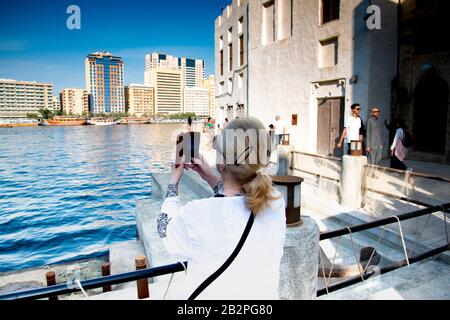 Indietro immagine di donna turistica scattando foto sul suo cellulare, a Dubai Creek UAE. Foto Stock