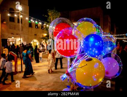 Colorato mazzo di palloncini in primo piano, con il turista passeggiando passato sullo sfondo, di notte in un mercato Square.Old Town, Dubai. Foto Stock