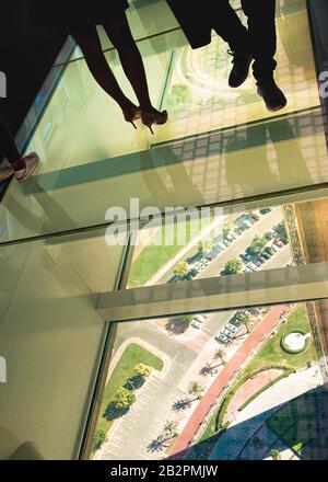 Silhouette delle gambe solo femminili e maschili, in piedi su passerella/pavimento in vetro situato sulla Dubai Frame, Foto Stock