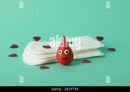 Assorbenti igienici, gocce decorative di sangue e piccoli cuori su sfondo di menta, closeup Foto Stock