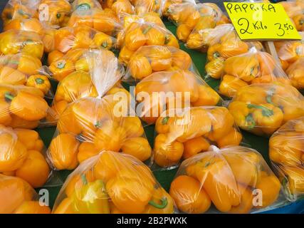 Molti peperoni gialli (parola tedesca sul segno: Paprika) in sacchetti di plastica sul mercato olandese Foto Stock