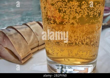 bicchiere di birra un pezzo di sgombro affumicato freddo su un piatto bianco sullo sfondo Foto Stock