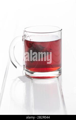 Tè di frutta in tazza di vetro su tavolo bianco. Foto Stock