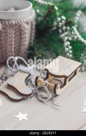 Primo piano di un ornamento di una slitta di legno circondato da decorazioni natalizie sul tavolo Foto Stock