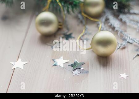 Closeup di ornamenti di Natale dorati con le stelle piccole su un tavolo di legno sotto le luci Foto Stock