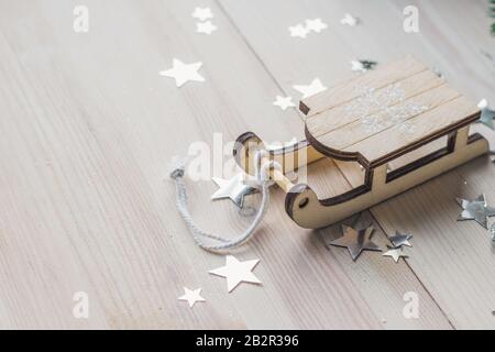 Primo piano di un piccolo ornamento di slitta di legno sul tavolo sotto le luci Foto Stock