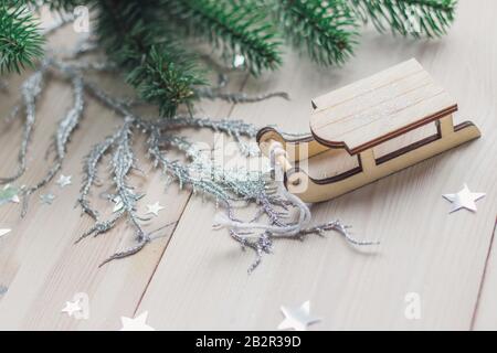 Primo piano di un piccolo ornamento di slitta di legno sul tavolo sotto le luci Foto Stock