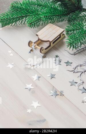 Primo piano di un piccolo ornamento di slitta di legno sul tavolo sotto le luci Foto Stock