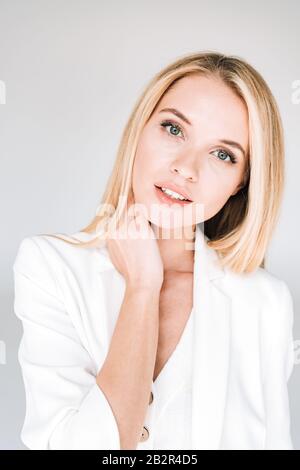 ritratto di bella giovane bionda donna in vestito bianco totale isolato su grigio Foto Stock