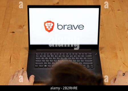 Vista dall'alto di un uomo seduto alla scrivania utilizzando un computer portatile con il logo del browser Brave sullo schermo. Foto Stock