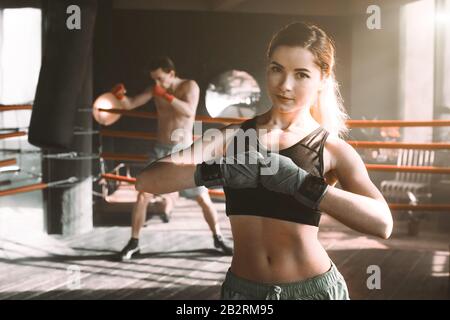 Boxer femmina facendo shadow boxing all'interno di un anello di inscatolamento. Boxer di mettere in pratica le sue mosse presso un studio di inscatolamento. Foto Stock