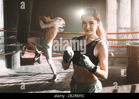 Boxer femmina facendo shadow boxing all'interno di un anello di inscatolamento. Boxer di mettere in pratica le sue mosse presso un studio di inscatolamento. Foto Stock