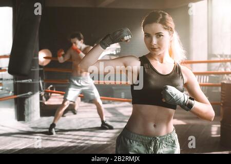 Boxer femmina facendo shadow boxing all'interno di un anello di inscatolamento. Boxer di mettere in pratica le sue mosse presso un studio di inscatolamento. Foto Stock