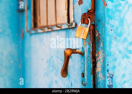 Vecchia porta industriale in metallo bloccata con lucchetto in ottone, s elettiva messa a fuoco Foto Stock