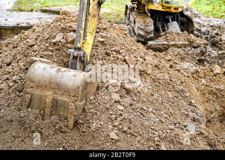 Benna in acciaio di un miniescavatore appoggiata su un cumulo di terra dopo lo scavo Foto Stock