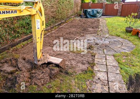 Cardiff, GALLES - GENNAIO 2020: Benna e braccio di un miniescavatore scavando il prato nel giardino posteriore di una proprietà residenziale Foto Stock