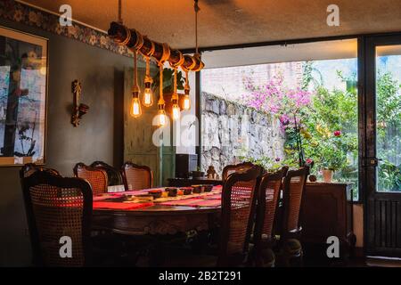 Lampadario rustico fatto di bulbi e corde sopra un pranzo tavolo in una cucina d'epoca Foto Stock
