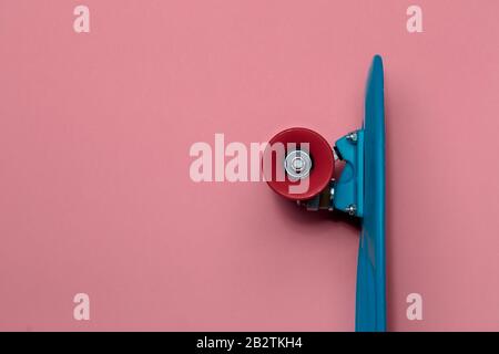 Crociera con skateboard blu con ruote rosse su sfondo rosa con spazio di copia Foto Stock