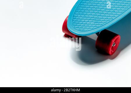 Crociera con skateboard blu con ruote rosse su sfondo bianco e spazio per le copie Foto Stock