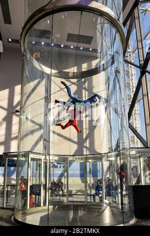 Novizio uomo alla scoperta di iFLY Parigi coperta galleria del vento skydiving in Vill'up centro commerciale presso il Parc de la Villette a Parigi, guidato da un istruttore. Foto Stock