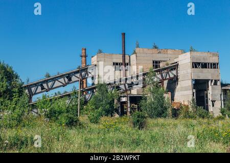 Vecchia fabbrica abbandonata overgrown di cemento armato. Foto Stock